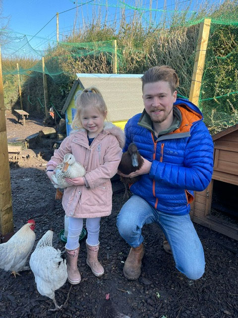 man and daughter holding ducks